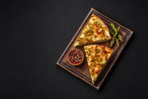 Finom quiche brokkolival, sajttal, csirkével, fűszerekkel és fűszernövényekkel sötét beton alapon - Fotó, kép