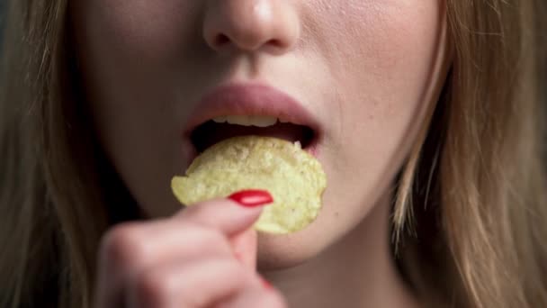 Detailní záběr ženských rtů a úst pojídajících lahodné hranolky. Šťastná a pozitivní mladá žena si dává jídlo na jazyk a žvýká. nezdravé a chutné jídlo - Záběry, video