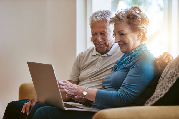 Ευτυχισμένο ζευγάρι ηλικιωμένων, καναπές και συζήτηση με φορητό υπολογιστή για περιήγηση, online αγορές ή χρηματοδότηση στο σπίτι. Ηλικιωμένοι άνδρες και γυναίκες που συζητούν για συνταξιοδότηση ή συνταξιοδοτικό ταμείο στον υπολογιστή στο σαλόνι στο σπίτι. - Φωτογραφία, εικόνα