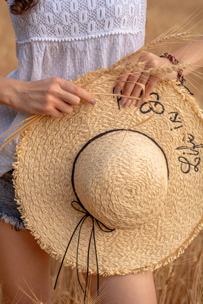 Nyári kalap széles karimával női kezekben, közelkép - Fotó, kép