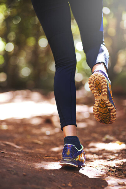 Shoes, runner or person running on trail in nature on outdoor adventure to explore in terrain footwear. Athlete, forest or hiker trekking in woods for training, wellness or travel journey for fitness. - Photo, Image