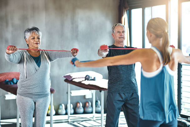 Stretching band, support and senior people in physical therapy for help with muscle training by physiotherapist. Exercise, workout and strength progress of mature clients in wellness class or gym. - Φωτογραφία, εικόνα