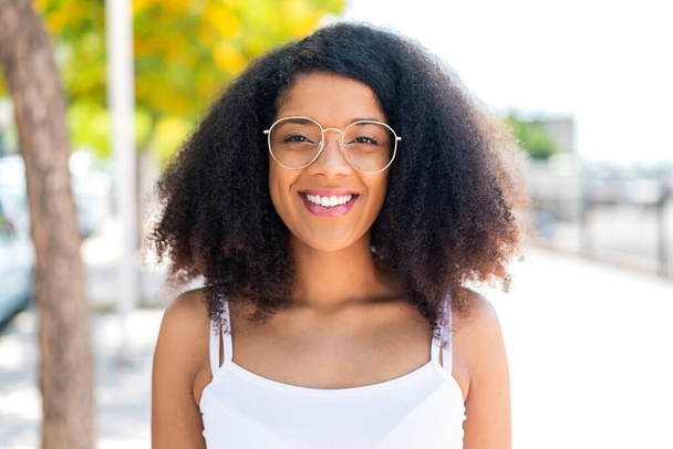 Jovem afro-americana ao ar livre com óculos com expressão feliz - Foto, Imagem