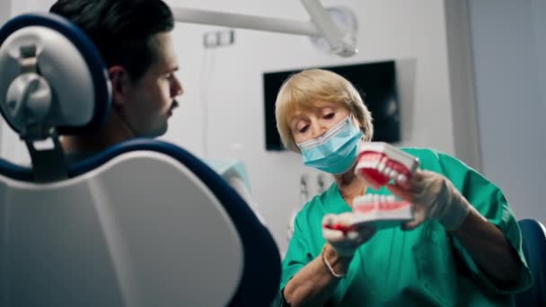 em uma clínica odontológica um dentista mostra a um paciente como escovar os dentes corretamente - Filmagem, Vídeo