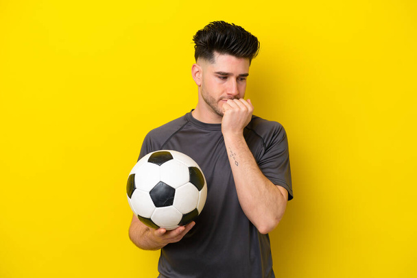 przystojny młody piłkarz człowiek odizolowany na żółtym tle mając wątpliwości - Zdjęcie, obraz