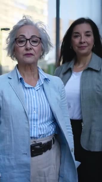 Vertical. Portrait of only mature Caucasian business women in formal suits posing serious with arms crossed looking confident at camera. Empowered and successful female entrepreneurs powerful outdoors - Video