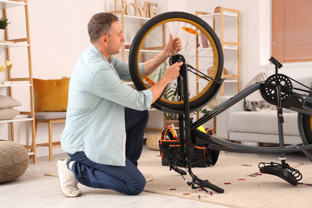 Зрілий чоловік ремонтує велосипедне колесо вдома - Фото, зображення