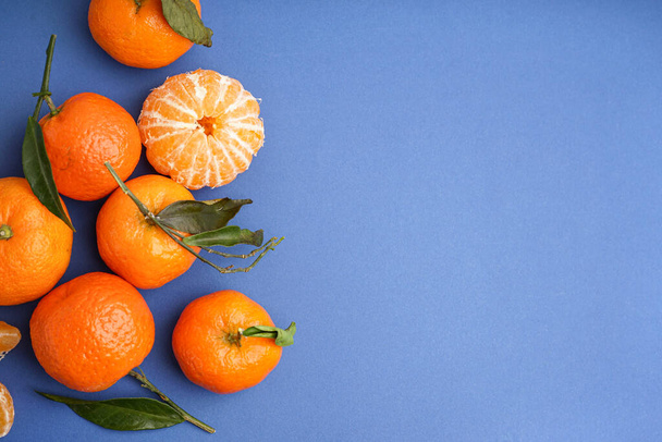 Tasty tangerines with leaves on blue background - Fotoğraf, Görsel