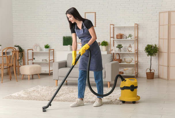 Jovem chão de limpeza mulher com aspirador de pó na sala de estar - Foto, Imagem
