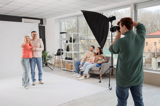 Male photographer taking picture of family in studio - Foto, Bild