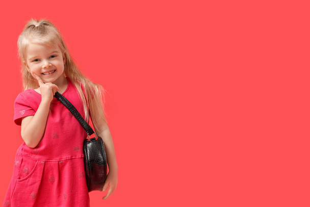 Cute little girl with stylish black bag on red background - Foto, Imagem