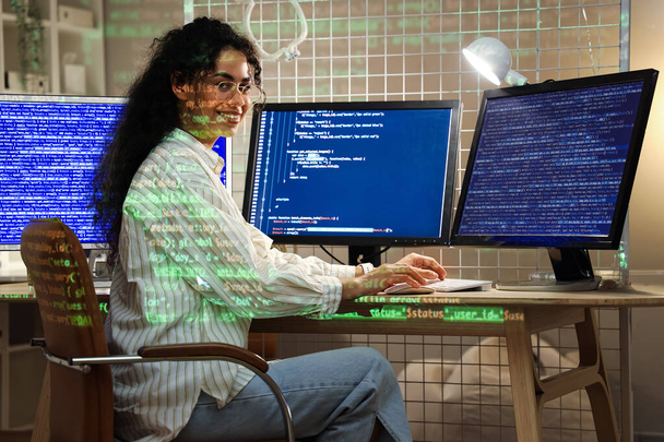 Γυναίκα Αφροαμερικανός προγραμματιστής με οθόνες υπολογιστών που εργάζονται στο γραφείο τη νύχτα - Φωτογραφία, εικόνα