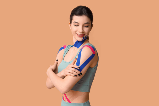 Young sporty woman with physio tape on color background - Zdjęcie, obraz