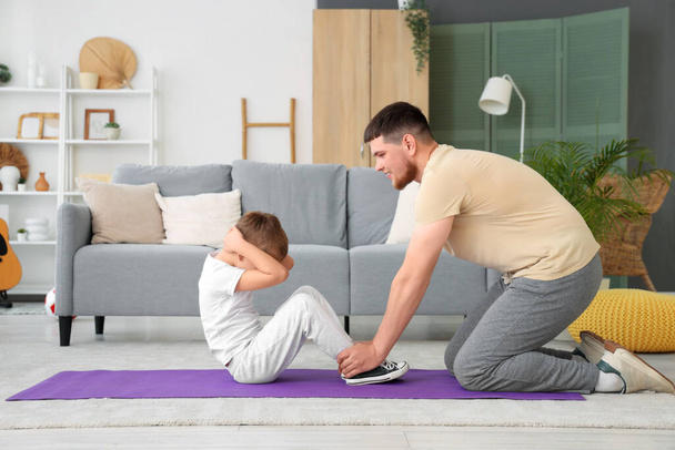 Young man and his little son doing exercises in living room - Valokuva, kuva