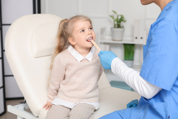 Male pediatrician examining little girl with tongue depressor in clinic - Φωτογραφία, εικόνα