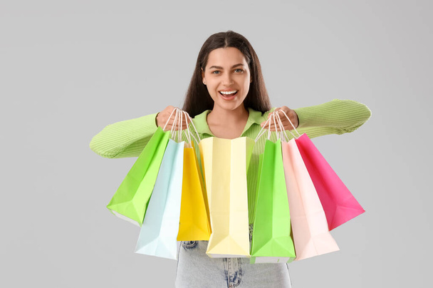 Beautiful young happy woman with shopping bags on grey background. Summer sale concept - Photo, image