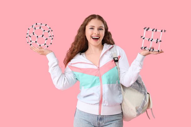 Happy female student with backpack and molecular models on pink background - Fotó, kép