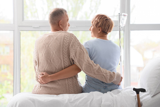Mature couple hugging on bed in clinic, back view - Fotografie, Obrázek