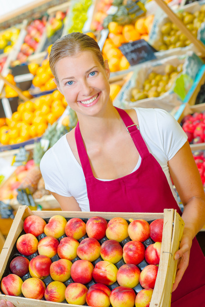 Shop assistant holding tray of nectarines - Foto, Bild