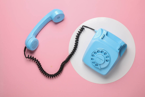 Ретро синий окрашенный вращающийся телефон на розовом фоне с белым кругом. Вид сверху. Минимализм - Фото, изображение