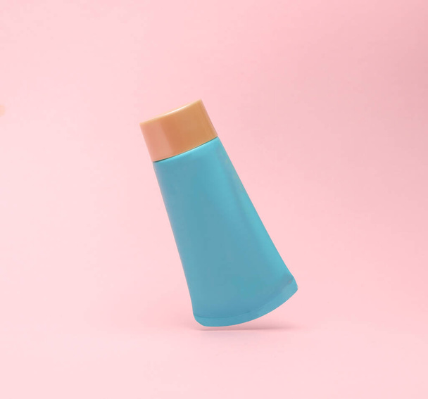 Blauwe crème buis zwevend in anti-zwaartekracht op een roze achtergrond. Mockup, sjabloon voor ontwerp - Foto, afbeelding