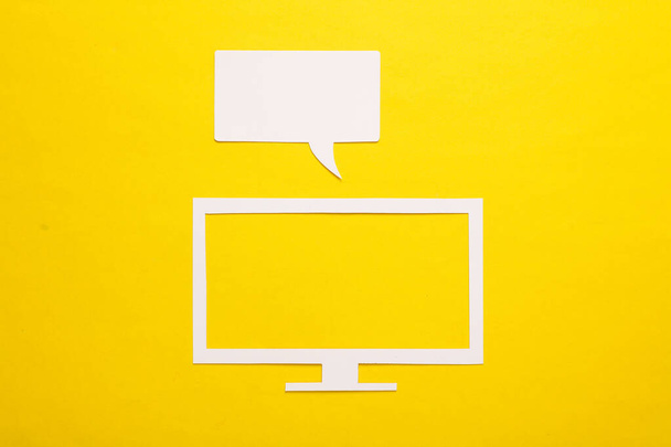 Icono de corte de papel de un televisor moderno con burbuja de voz sobre fondo amarillo - Foto, Imagen