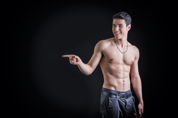 Shirtless young man laughing and pointing finger to a side - Фото, зображення
