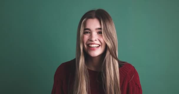Молода жінка сміється з камери в студії з зеленим фоном - Кадри, відео