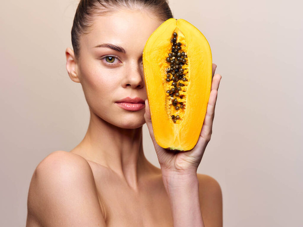 Portrait of a beautiful young woman with papaya fruit on her face, isolated on white background, skincare and beauty concept - Photo, Image