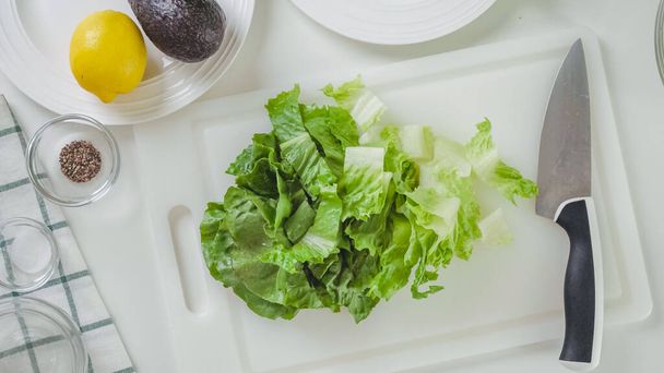 Levelek friss zöld saláta közelről fehér vágódeszka, lapos tojásrakás. - Fotó, kép