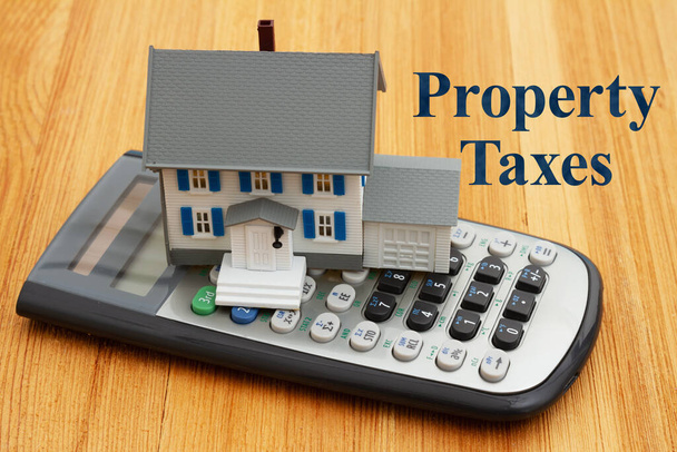 Déterminer vos impôts fonciers avec une maison et une calculatrice sur un bureau en bois - Photo, image
