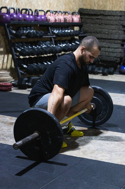 Повне тіло зосередженого іспаномовного бородатого спортсмена з важким штангою для тренувань під час тренувань з важкої атлетики у спортивному центрі - Фото, зображення
