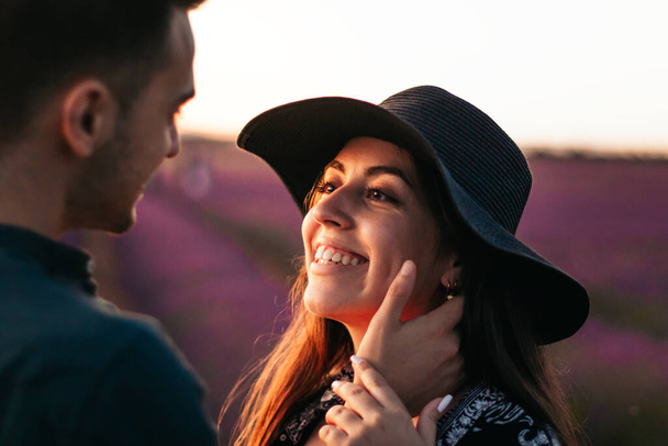 Close-up de um jovem e mulher apaixonados em um campo de lavanda ao pôr-do-sol, olhando um para o outro e prestes a se beijar - Foto, Imagem