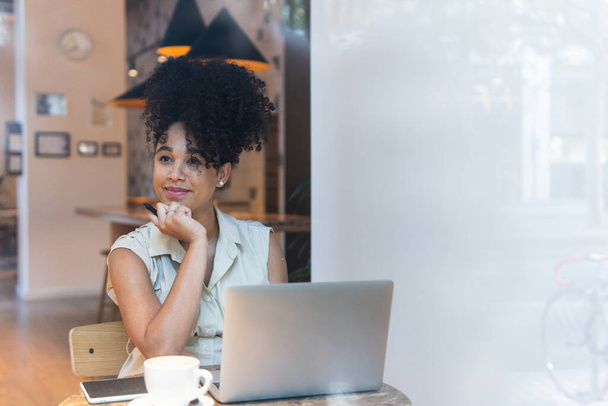 Pozytywne African American freelancer za pomocą tabletu graficznego przy stole z laptopem i kawą - Zdjęcie, obraz