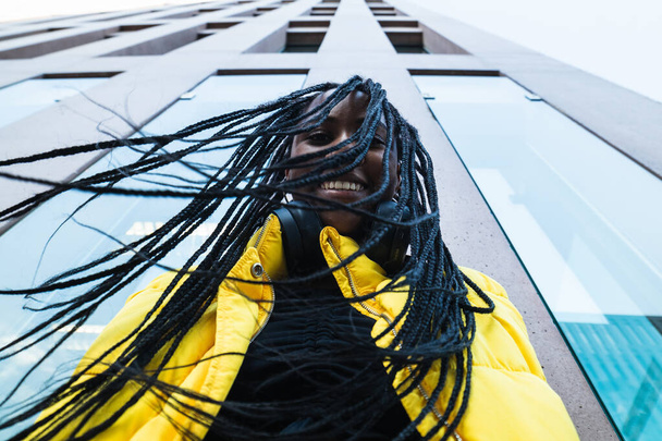 若いアフリカ系アメリカ人女性の下から,カメラを見ている街路の近代的な高層ビルの外に立っているブレード - 写真・画像