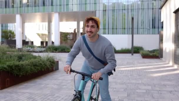 Щасливий молодий студент виходить з кампусного коледжу після уроків катання на велосипеді. Освіта, люди та концепція екологічно дружнього транспорту.  - Кадри, відео