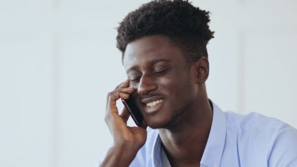 Mobil pazarlıklar. Genç Afrikalı Amerikalı adam ev telefonuyla konuşuyor, kapat. - Video, Çekim