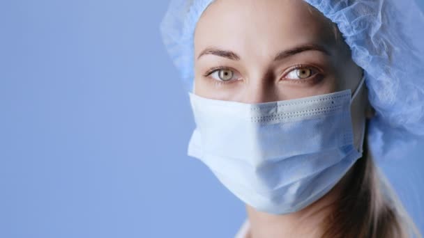 Portrét zdravotníka. Sebevědomá lékařka v ochranné masce obličeje a klobouku při pohledu do kamery - Záběry, video