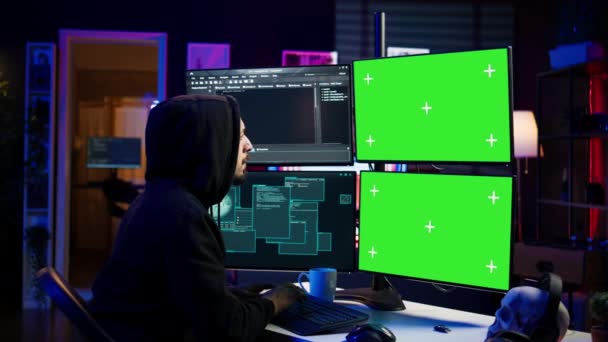 Hacker développant des logiciels espions sur ordinateur à écran vert pour voler des données importantes à vendre sur le marché noir. Scammer à capuchon écriture de code malveillant sur chroma key PC, caméra B - Séquence, vidéo