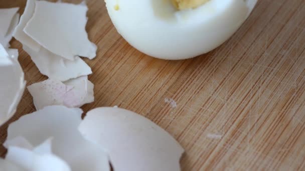 Stłuczona skorupa jajka na drewnianej desce do krojenia - Materiał filmowy, wideo