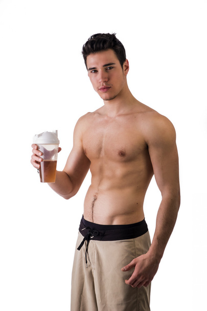 Athletic shirtless young man holding protein shake bottle, ready for drinking - Photo, image