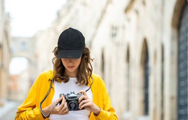 Chica con una cámara vintage en una calle vieja. - Foto, Imagen