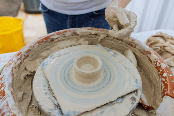 Creating clay dishes on potter wheel, a potter hand sculpts soft clay with wet hands - Photo, Image
