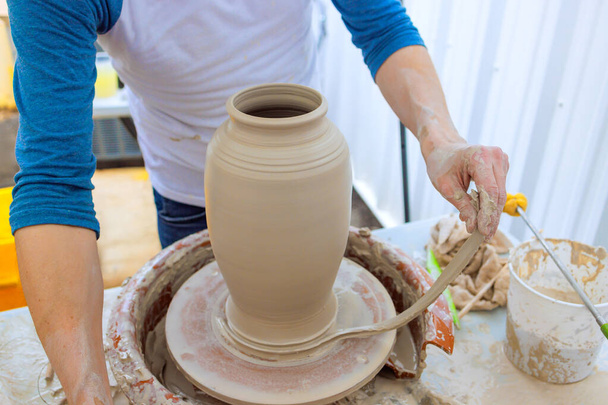 An potter hand sculpt shaping soft clay with wet hands on potter wheel - Photo, Image