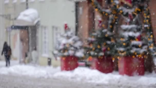 Святкова міська вулиця під повільним снігом, з пішоходами на відстані - Кадри, відео