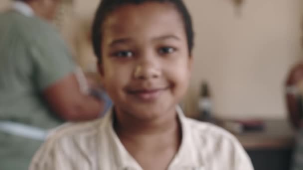 Extrémní detail zoom-in portrét veselý 10-letý Afroameričan chlapec se usmívá a dívá se do kamery, rodina vaření večeře v kuchyni v rozmazaném pozadí - Záběry, video