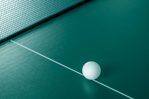 Настольный теннисный мяч на столе в прохладной цветовой гамме. - Фото, изображение