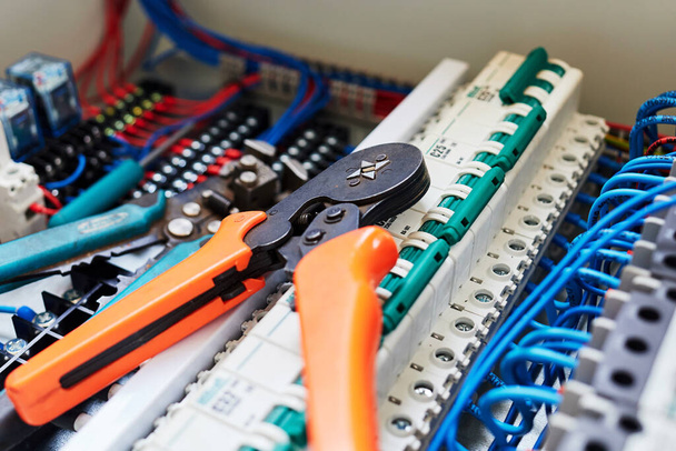 narzędzia elektryczne i niebieskie przewody podłączone do listwy stykowej i przekaźników. - Zdjęcie, obraz