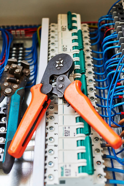 Elektrische Werkzeuge und blaue Drähte, die mit der Kontaktleiste und den Relais verbunden sind. - Foto, Bild