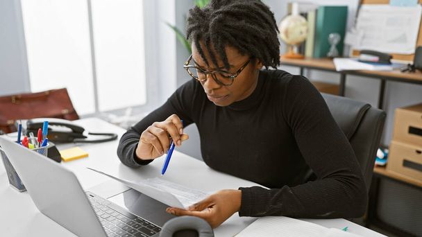 Focused young woman with dreadlocks working on documents in a modern office interior. - Photo, Image